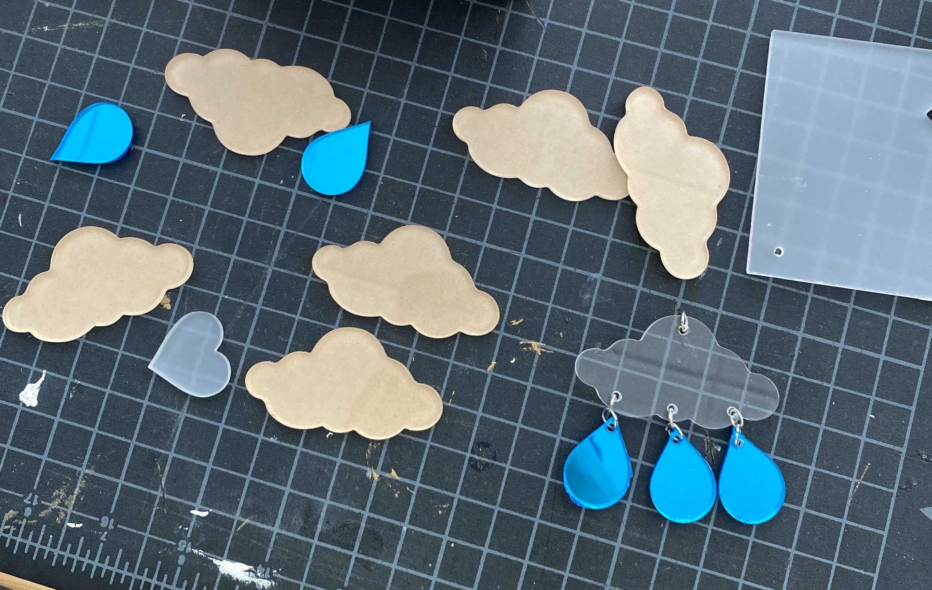 Image of laser cut acrylic pieces in the shape of clouds and raindrops