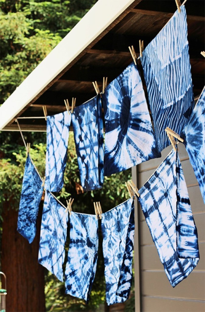 Image of 6 blue shibori tie-dyed pieces of fabric, hanging on a clothes line.