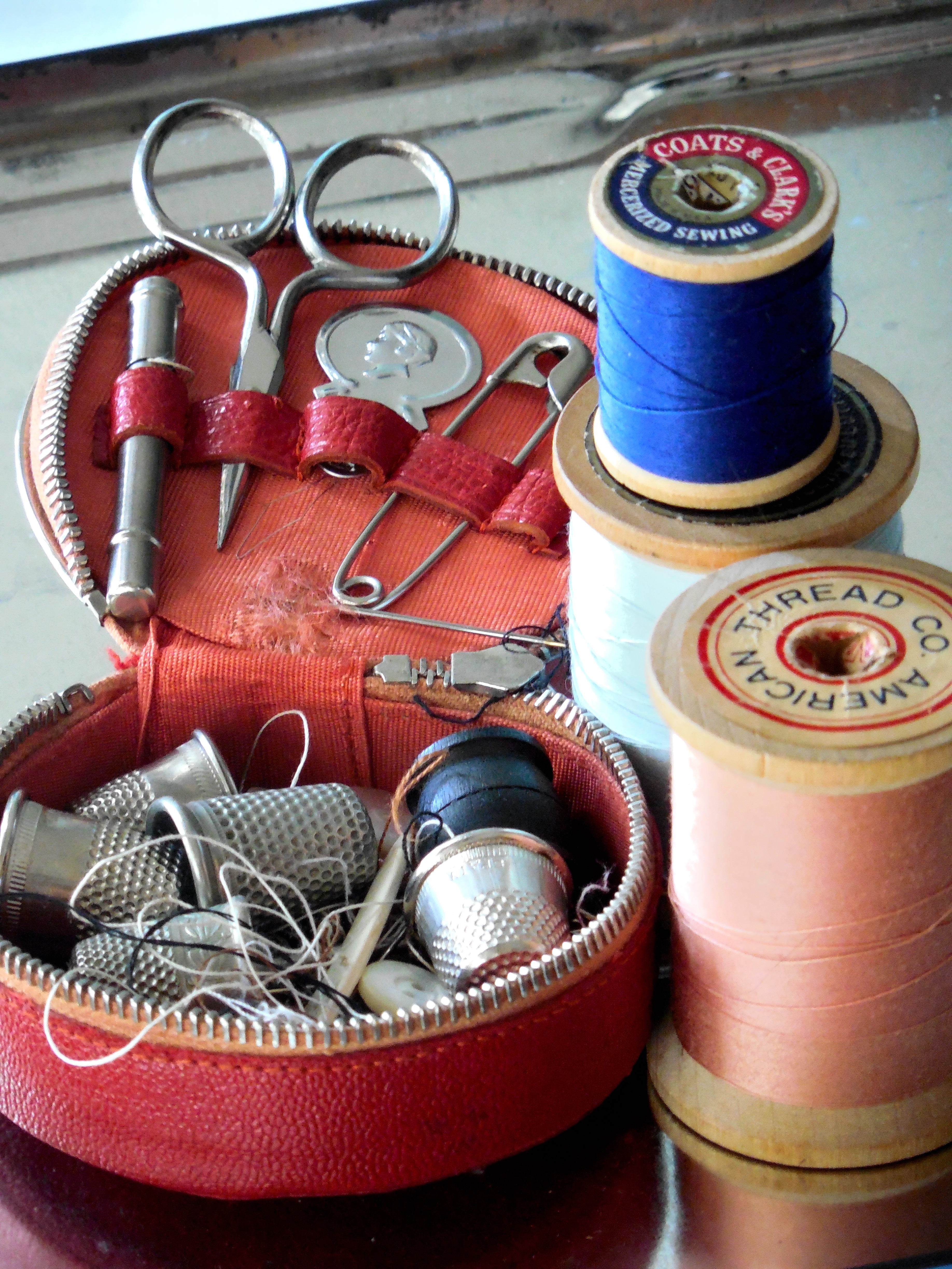 2 spools of thread with sewing supplies (scissors, thimbles) in a red bag