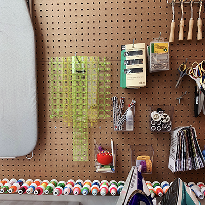 image of peg board with various sewing accessories hanging from it