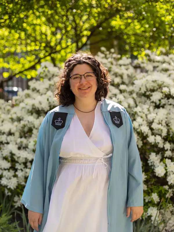 Image of Mary Clare Greenlees in a blue Columbia graduation gown and white dress.
