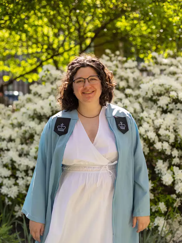 Image of Mary Clare Greenlees in a blue Columbia graduation gown and white dress.