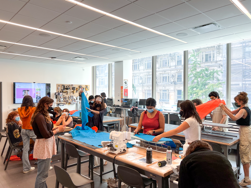 photo of fifteen students in the Design Center working on a class project with sewing machines