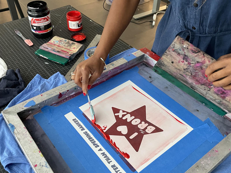 Student applies ink to silk screen for printing