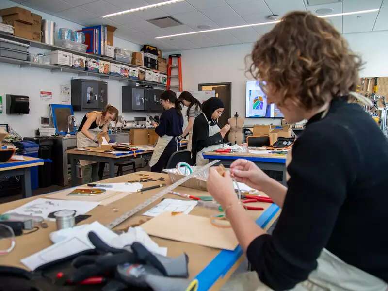 Photo of student working on a stained glass project in the Design Center, with other students working in the background.