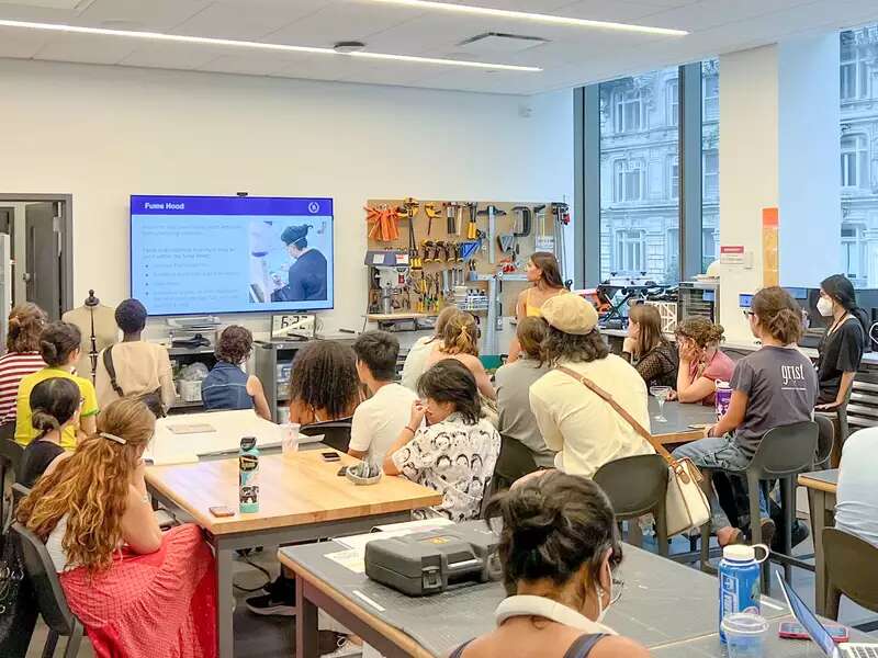 A group of students watch a power point presentation in the Design Center. 